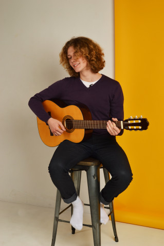 Молодой парень с кучерявыми волосами играет на гитаре